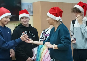 Wychowawczyni klasy VII B rozdaje czekoladowe mikołaje swoim uczniom.