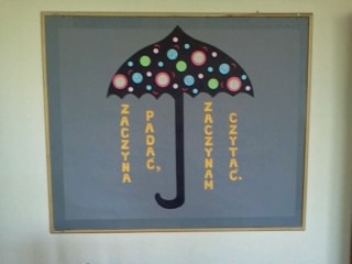 Tablica okolicznościowa przygotowana w bibliotece szkolnej. Kolorowa parasolka, obok napis ,,Zaczyna padać - zaczynam czytać".
