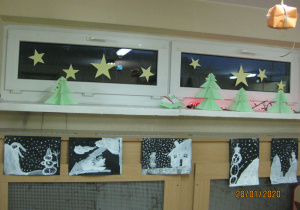Zimowe prace uczniów wykonane techniką malarską. Bałwanki i śnieżynki namalowane białą farbą na czarnym kartonie.