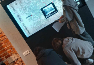 Dziewczynki rozwiązują zadania z mapą przed mapą cyfrową