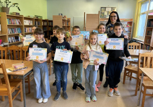 Zdjęcie uczniów klas trzecich podczas wręczenia nagród w bibliotece szkolnej.