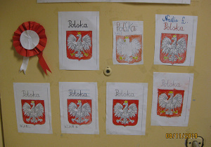 Przyklejone do ściany prace uczniów - pokolorowane kredkami godła Polski