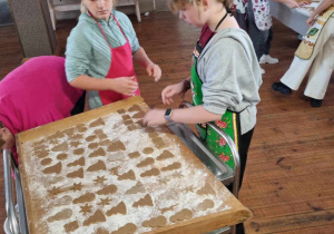 Uczestnicy zajęć układają na stolnicy pierniki do pieczenia