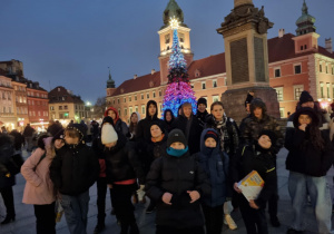 Uczestnicy wycieczki przed Zamkiem Królewskim w tle choinka