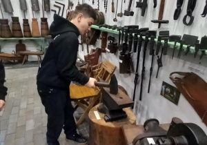 Uczeń w izbie w Galerii Staroci z młotkiem w ręce