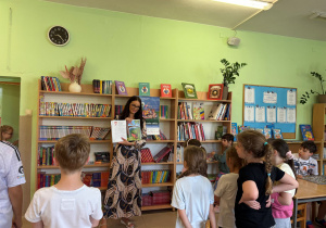 Nauczyciel czyta książkę dzieciom w bibliotece szkolnej.