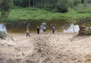 Uczestnicy wycieczki na plaży nad meandrująca Grabią
