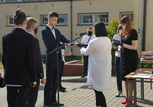 Pani dyrektor wręcza uczniowi klasy VIII nagrodę.