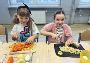 Klara i Łucja wspólnie przygotowują składniki sałatki.