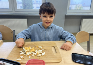 Tymon ostrożnie kroi jajko.