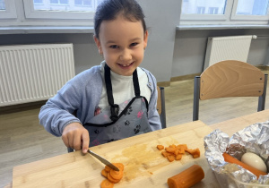 Hania z pełnym zaangażowaniem kroi marchewkę.