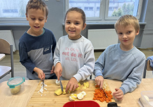Bolek, Veronika i Antek współpracują podczas krojenia warzyw.