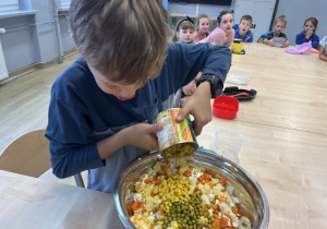 Bolek dosypuje kukurydzę do sałatki.