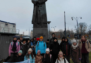 Uczestnicy zajęć przy pomniku marszałka z flagą Polski