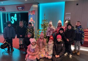 Uczniowie klasy 1b pozują w kinie przy choince.