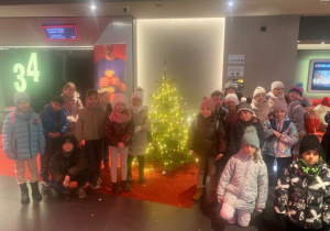 Uczniowie klasy 1c pozują w kinie przy choince.