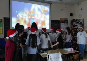 Uczniowie w czapkach Mikołaja śpiewają kolędę Świeć gwiazdeczko