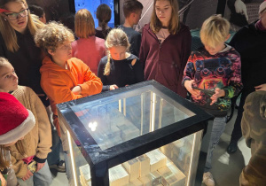 Uczestnicy warsztatów przy szklanej szkatułce z milionem złotych w banknotach 10- złotowych