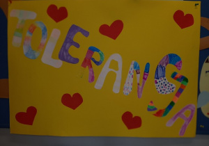Plakat- na żółtym tle znajduje się kolorowy napis TOLERANCJA oraz czerwone serca. Prace wykonane pod opieką Pani P. Filipczak.