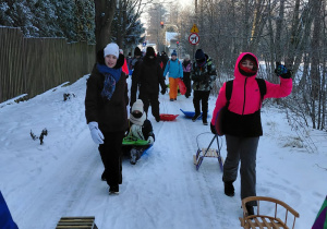 Uczestnicy zajęć z sankami w drodze ulicą Raduńską na górkę