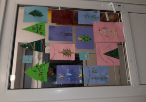 Choinki wywieszone na szklanych drzwiach. Prace wykonane pod opieką Pani P. Filipczak