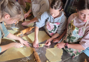 Uczestnicy zajęć kroją ciasto na paski i tworzą faworki