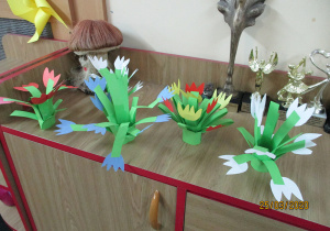 Tulipany- prace dzieci wykonane z kolorowego papieru, ustawione na szafce.