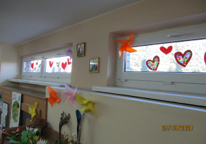 Wiosenna dekoracja świetlicy. Czerwone serduszka na szybach, kolorowe wiatraki przyklejone do okien i ściany.