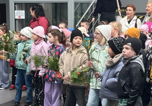 Dzieci z zielonymi gałązkami przed wymarszem w holu GOK