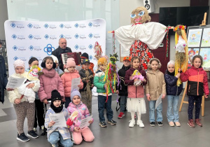 Burmistrz Rzgowa z uczniami klas pierwszych i instruktorem muzycznym w holu Gminnego Ośrodka Kultury