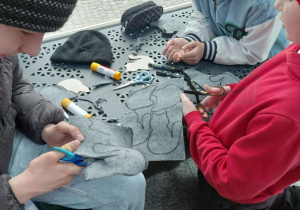 Chłopcy wycinają filcowe koty.