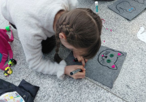 Uczestniczka warsztatów ozdabia filcowego kota - podkładkę.