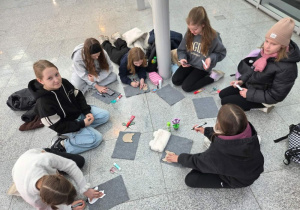 Dziewczynki odrysowują koty z szablonu na filcu.