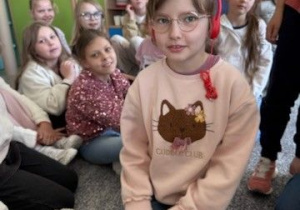 Uczennica w słuchawkach w otoczeniu uczniów klasy 2 B