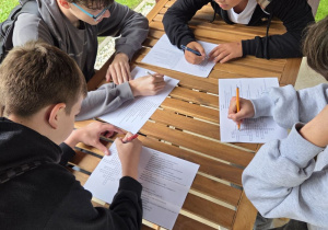 Uczniowie rozwiązują test wiedzy z terenowej lekcji w postaci krzyżówki.