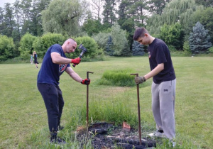 Panowie przygotowują stojak na garnek, który zawiśnie nad ogniem