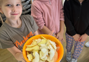 Marianka, Hania i Lucynka z uśmiechem prezentują pokrojone w plastry jabłka.