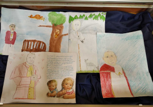 Prace uczniów wykonane kredkami i farbami przedstawiające wizerunek Jana Pawła II.