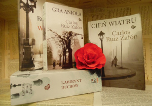 Zdjęcie przedstawia cztery książki Carlosa Ruiza Zafóna, które składają się na cykl „Cmentarz Zapomnianych Książek”, skierowane do dorosłego czytelnika. Książki zostały ustawione na regale wystawowym w bibliotece. Między nimi znajduje się kwiat, wykonany z czerwonej bibuły.