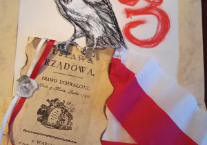 Plakat ucznia z napisem 3 maj, rysunkiem orła białego oraz pierwszą kartką Konstytucji.