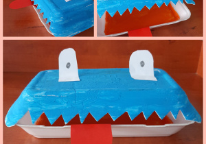 Pożeracz zużytych baterii wykonany z pudełka do przechowywania posiłków. Praca wykonana farbami w kolorach: niebieskim i pomarańczowym.