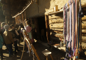 Niewielka grupa uczniów oglądająca wyroby z kości, drewna i tkanych pasów.