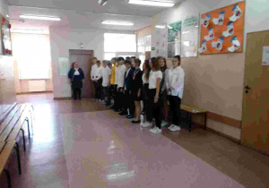 Uczniowie klasy VIIb stoją na korytarzu i śpiewają hymn. Budynek B, 2 piętro.