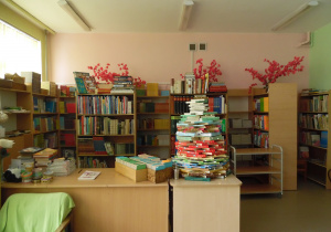 Zdjęcie przedstawia fragment wnętrza biblioteki (stanowisko bibliotekarza wraz z częścią księgozbioru podręcznego i lektur).