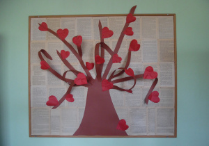 Zdjęcie przedstawia główną tablicę biblioteczną utworzoną w ramach zabawy bibliotecznej Randka w ciemno z książką - VIII EDYCJA. W centralnym miejscu znajduje się drzewo z czerwonymi serduszkami.