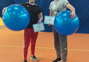 Panowie: Damian Słomczyński oraz Mariusz Matecki trzymający dyplomy ukończenia szkolenia oraz piłki fitness
