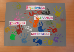 Plakat z napisami: życzliwość, tolerancja, akceptacja, szacunek. Na szarym kartonie formatu A1 odciśnięto dłonie kolorową farbą. Praca wykonana w gr. 1 pod opieką Pani Pauli Filipczak.