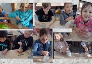 Uczniowie klasy II c podczas wykonywania doświadczenia ,,Krystalizacja soli". Dzieci mieszają przygotowany roztwór oraz wkładają do środka serduszko wykonane z kreatywnego drucika.