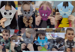 Uczniowie trzymają w rękach prace pt. ,,Kot”, która została wykonana techniką origami.