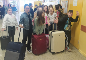 Uczniowie z walizkami na szkolnym korytarzu.